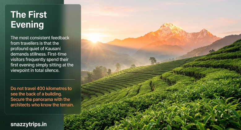 Scenic view of Kausani tea gardens during sunset with the sun casting golden light over lush green terraces and a snow-capped Himalayan peak in the background, capturing a peaceful and quiet evening atmosphere.